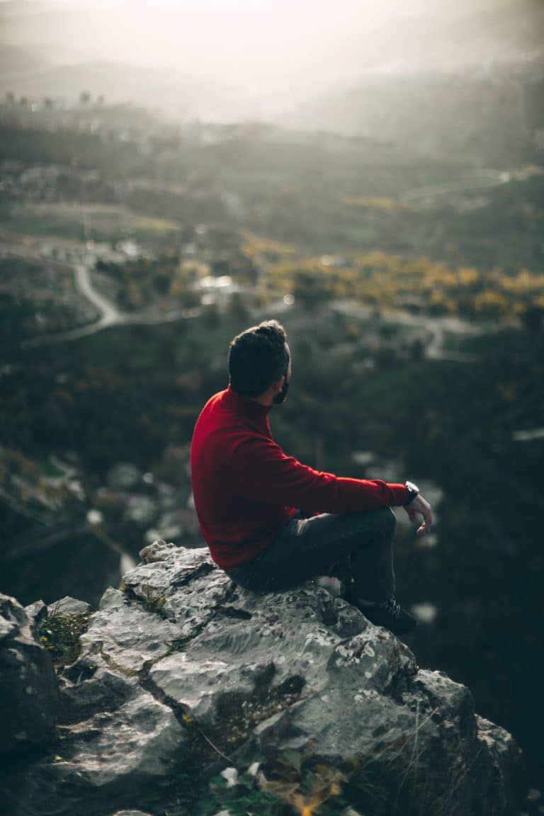Man sitting on a rock in a mountain thinking